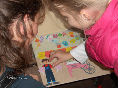 878120 Afbeelding van een meisje met haar moeder die een plakwerkje maken op de onlangs geopende tentoonstelling ...